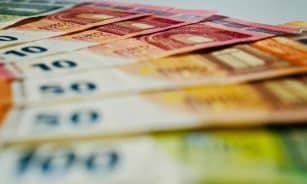 A close-up image of euro banknotes in various denominations spread out, showcasing currency details.