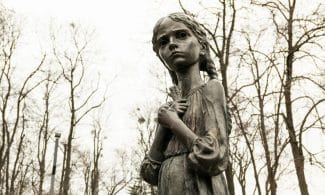Holodomor memorial statue in Kyiv, Ukraine, depicting a solemn girl in autumn park.