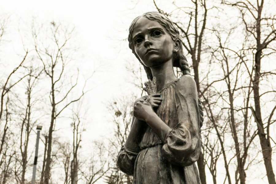 Holodomor memorial statue in Kyiv, Ukraine, depicting a solemn girl in autumn park.