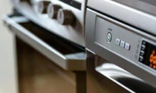 Close-up view of modern stainless steel kitchen appliances with focus on dishwasher and oven.