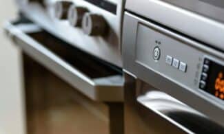 Close-up view of modern stainless steel kitchen appliances with focus on dishwasher and oven.