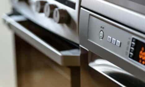 Close-up view of modern stainless steel kitchen appliances with focus on dishwasher and oven.