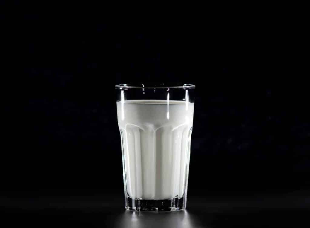 A glass of fresh milk against a black background, emphasizing simplicity and nutrition.
