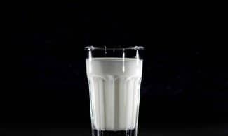 A glass of fresh milk against a black background, emphasizing simplicity and nutrition.