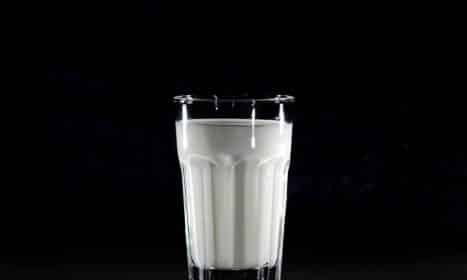A glass of fresh milk against a black background, emphasizing simplicity and nutrition.