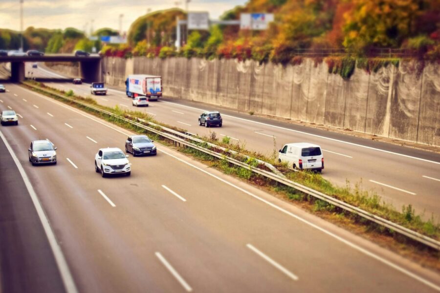 Cars and trucks moving on a highway under sunny skies, showcasing road travel.