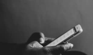 A monochrome image showing a person using a smartphone, emphasizing modern technology.