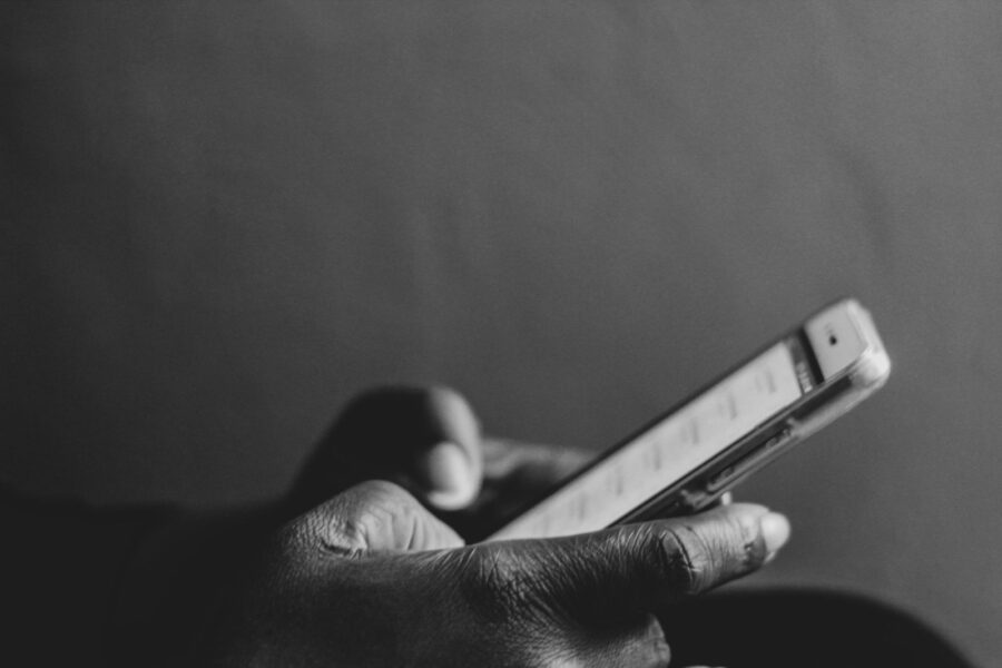 A monochrome image showing a person using a smartphone, emphasizing modern technology.