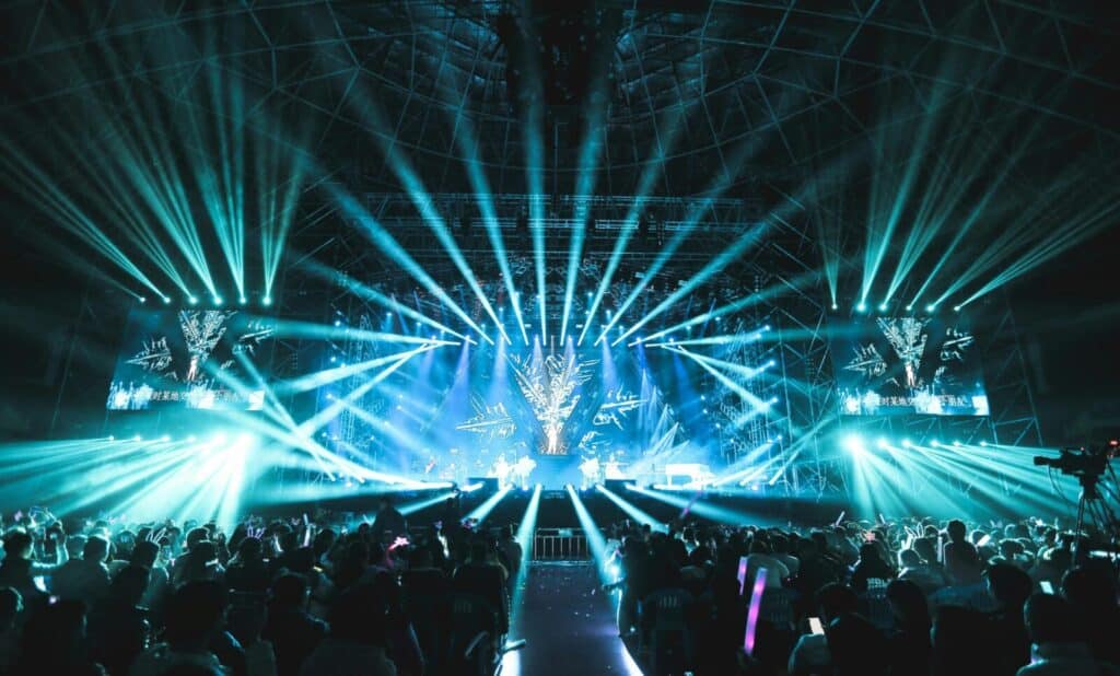 Lively concert scene featuring dazzling stage lights and a large, enthusiastic crowd enjoying the event.