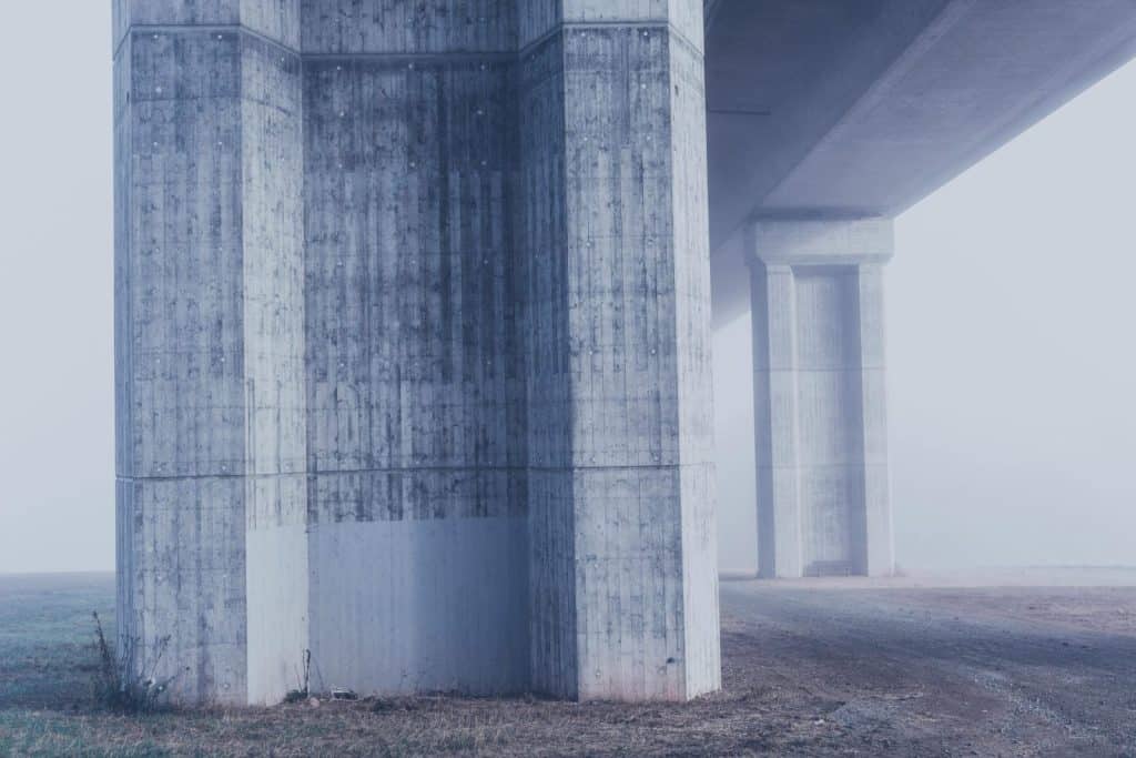 Misty view of concrete bridge columns in a foggy urban environment.
