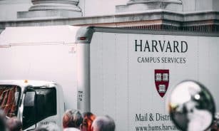 Harvard Campus Services truck in city street, showcasing delivery near university building.