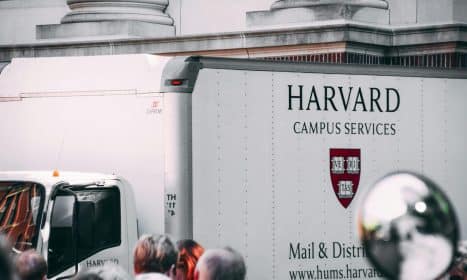 Harvard Campus Services truck in city street, showcasing delivery near university building.