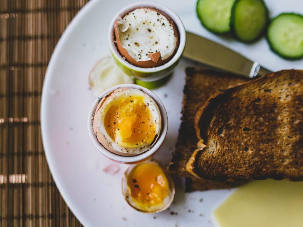 Top view of a breakfast plate featuring soft boiled eggs and toast, ideal for a nutritious meal.