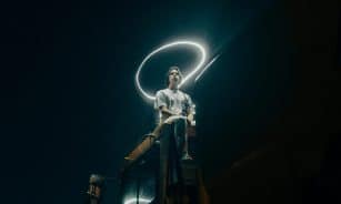 A man sits on a truck, surrounded by a light halo under a starry sky.