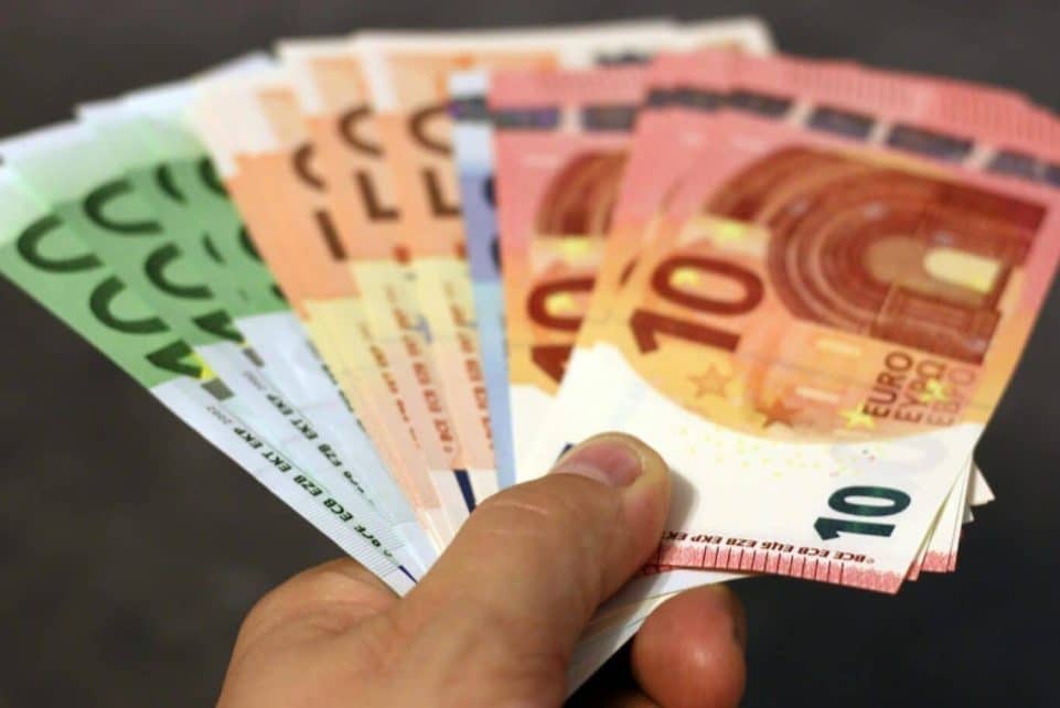 A fan of euro banknotes in various denominations held in a hand.