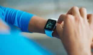 Person interacting with a smartwatch, showing a fitness application on the screen.