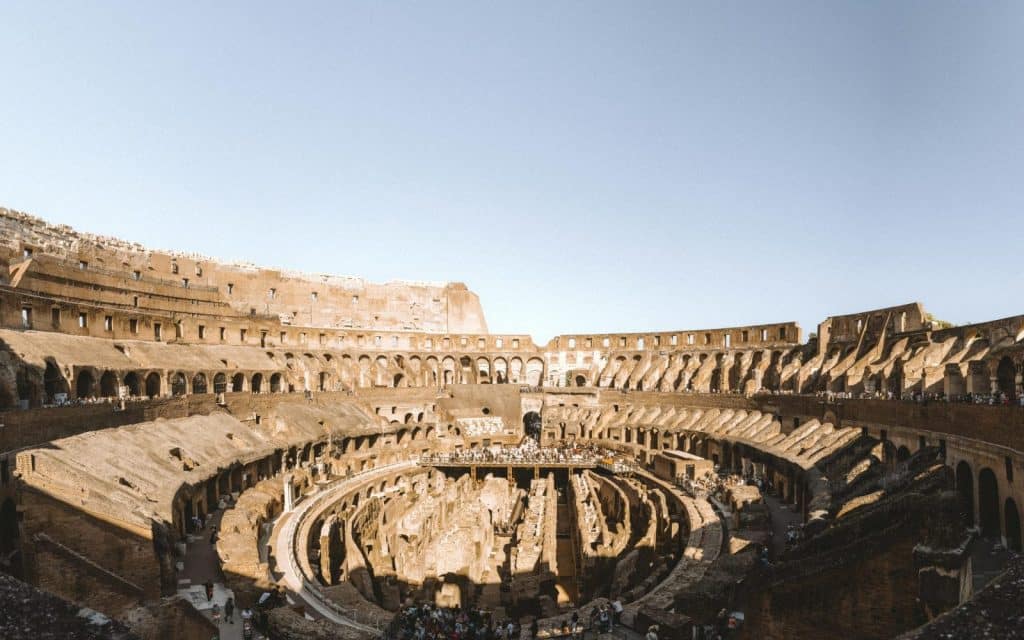 Explore the historic interior of the Colosseum in Rome, Italy, under a clear sky.