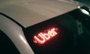 Close-up of a ride-sharing car with a bright red illuminated sign for night-time travel.
