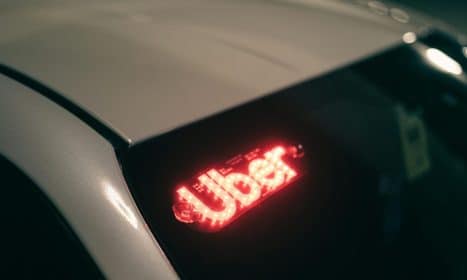 Close-up of a ride-sharing car with a bright red illuminated sign for night-time travel.