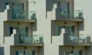 Architectural view of modern apartment balconies with sleek glass railings and outdoor furniture.