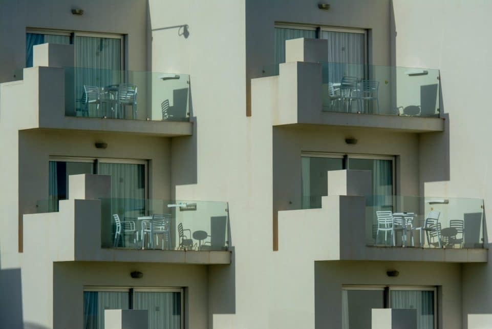 Architectural view of modern apartment balconies with sleek glass railings and outdoor furniture.
