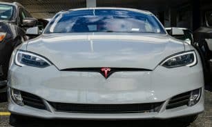 Front view of a Tesla Model S parked in an urban area, highlighting sleek design and modern aesthetics.