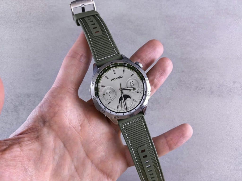 A detailed shot of a Huawei smartwatch with a green band being held in a hand.