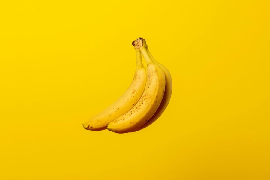 A bunch of ripe yellow bananas against a vivid yellow backdrop, offering tropical freshness.