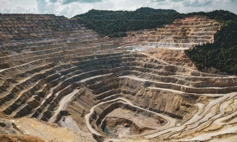 Aerial view of a large open-pit mine with terraced excavation during summer.