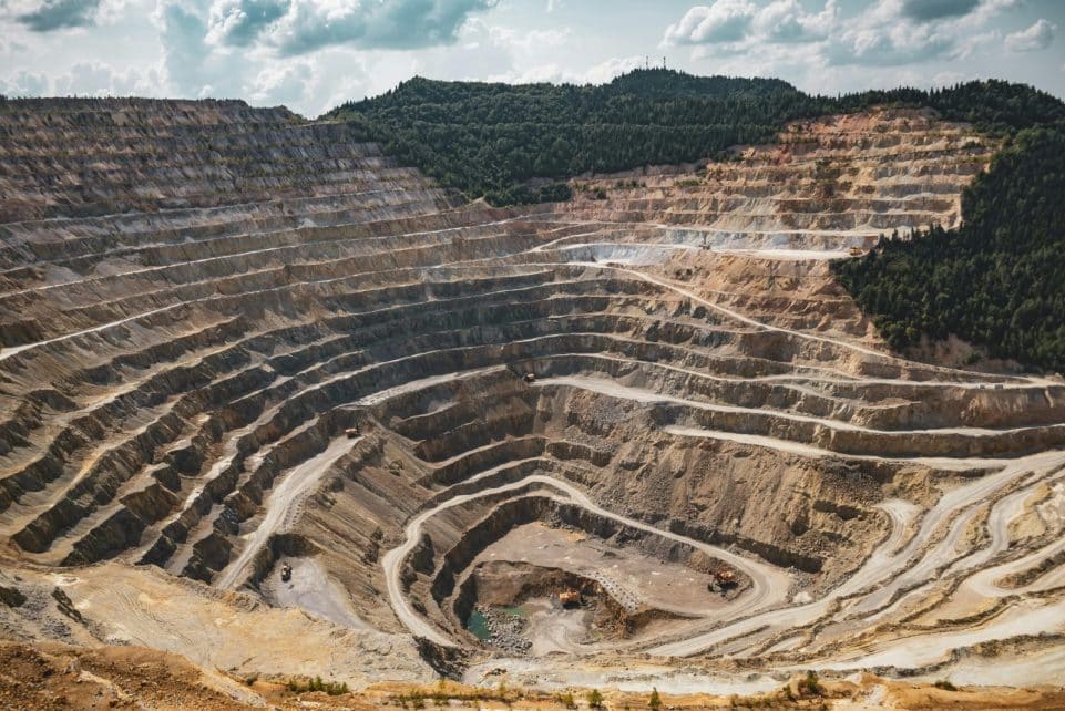 Aerial view of a large open-pit mine with terraced excavation during summer.