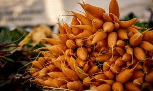A vibrant display of fresh heirloom carrots at a farmers market, showcasing natural and organic produce.