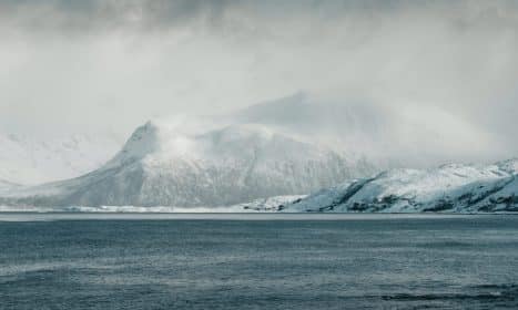 Scenic view of snow-capped mountains and ocean in Norway's Arctic region.