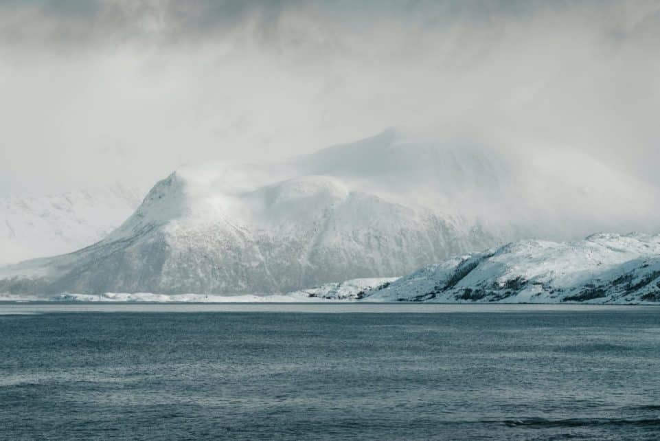 Scenic view of snow-capped mountains and ocean in Norway's Arctic region.