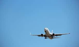 Virgin Australia aircraft captured mid-landing against a clear blue sky at Melbourne Airport.