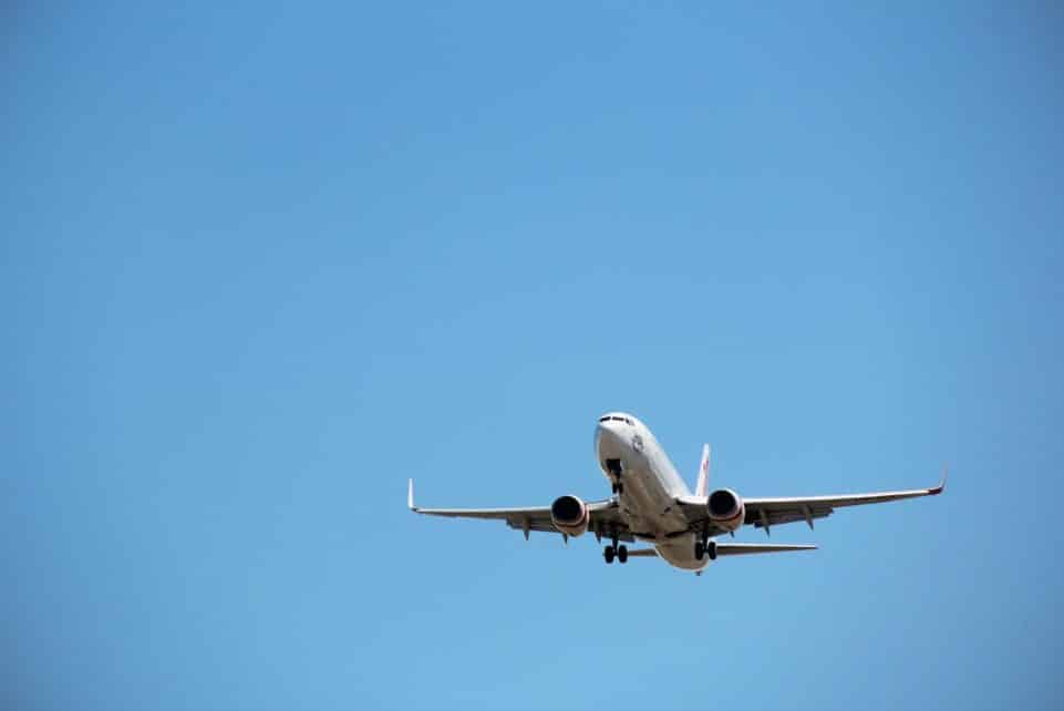 Virgin Australia aircraft captured mid-landing against a clear blue sky at Melbourne Airport.