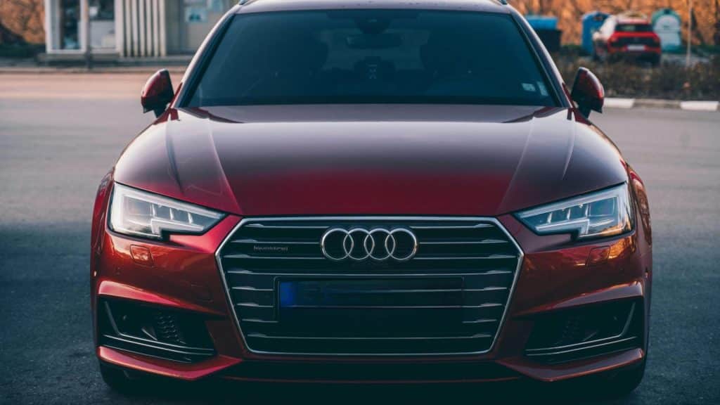 Sleek red Audi A4 shown from front in an urban backdrop, showcasing luxury and design.