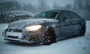 Luxury car covered in snow on a winter day, showcasing resilience and design.