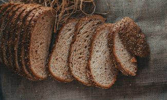 Sliced whole wheat bread arranged on burlap, showcasing crunchy texture and rustic appeal.
