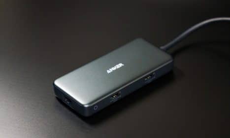 Compact USB-C hub on dark desk surface with visible USB ports.