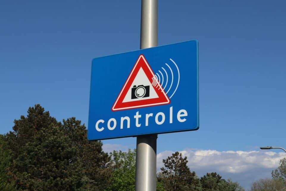 A blue road sign with a camera icon and 'controle' text indicates speed monitoring.