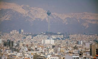 Aerial view of Tehran featuring Milad Tower against the Alborz Mountains.