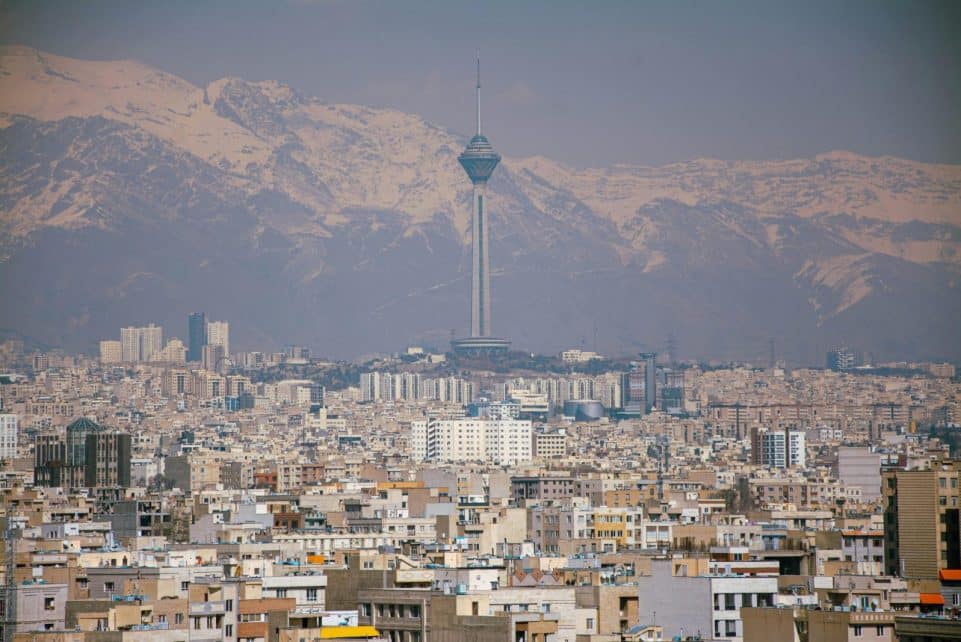 Aerial view of Tehran featuring Milad Tower against the Alborz Mountains.