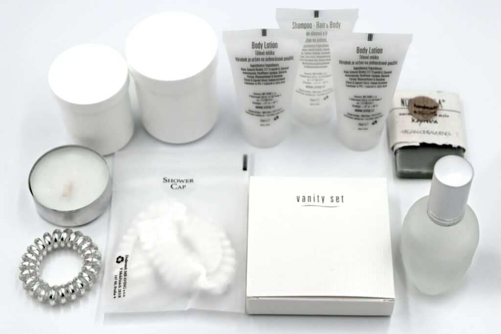Flat lay of luxury hotel toiletries and amenities, including body lotion, shampoo, and scented candles.