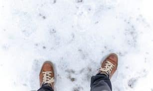 Casual brown leather shoes stepping on fresh white snow, capturing the essence of winter travel.
