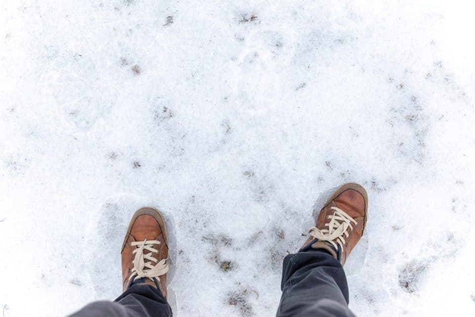 Casual brown leather shoes stepping on fresh white snow, capturing the essence of winter travel.