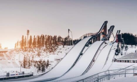 Snow-covered ski jumps in Lahti during winter golden hour with a serene and frosty landscape.