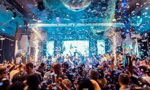 Vibrant nightclub scene in Mantua, Italy, featuring a lively crowd, confetti, and colorful lights.