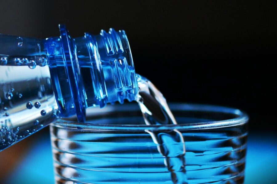 Close-up of sparkling water being poured from a bottle into a glass with bubbles visible.