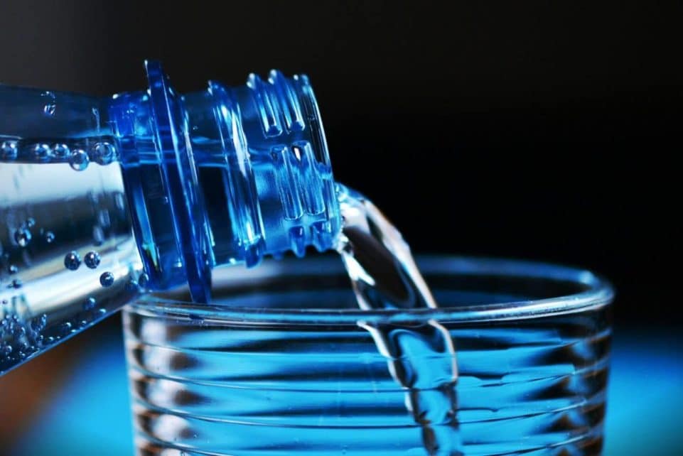 Close-up of sparkling water being poured from a bottle into a glass with bubbles visible.