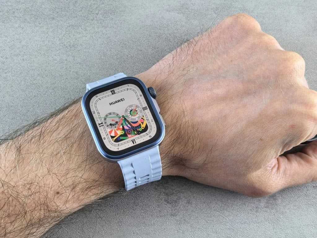 A detailed view of a Huawei smartwatch with a colorful display, worn on a human wrist.